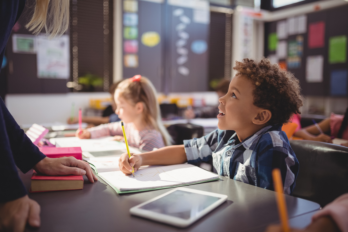 Teacher interacting with schoolboy in classroom