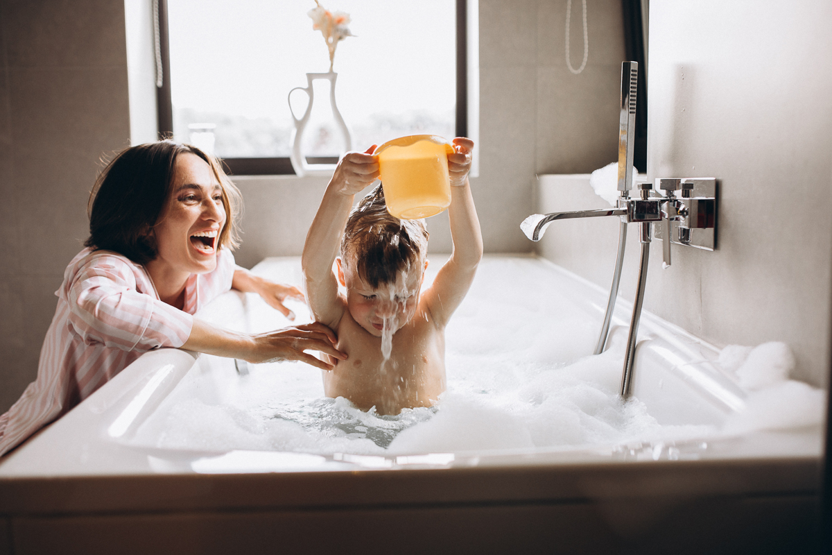 Mother washing little son in bathroom