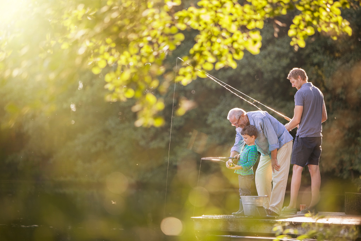 Boy, father and grandfather fishing in lake