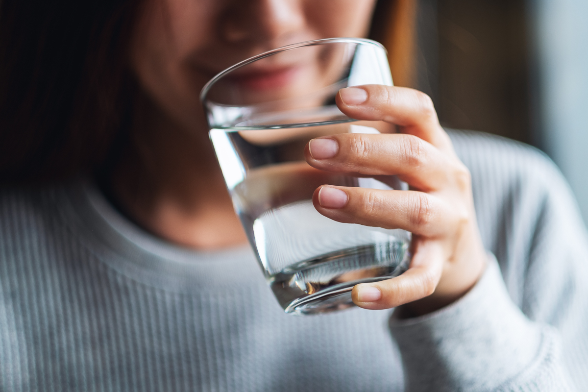 Closeup image of a beautiful young asian woman holding a glass of water to drink