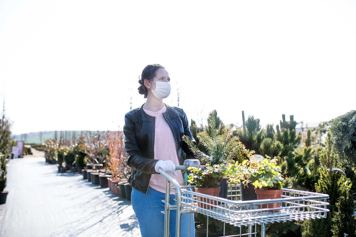 Young woman with face masks outdoors shopping in garden center, Corona virus concept.